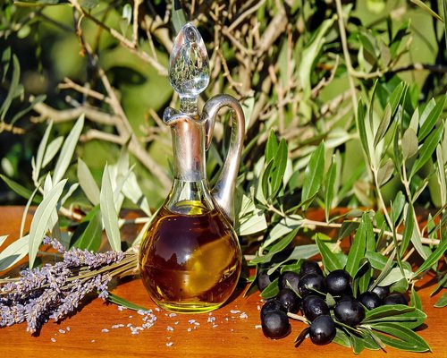 A variety of colorful organic vegetables and olive oil on a wooden kitchen table